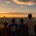 Silhouetten von Männern und Jungen, die in einer informellen Siedlung in Nairobi zusammenstehen — Sinnbild für Gemeinschaft und das Brechen des Schweigens.